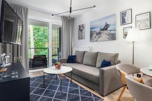 a living room with a couch and a table at Pobierowo Plaża & SPA - Apartament na Wydmach by Noclegi Renters in Pobierowo