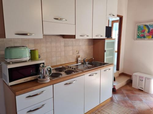 a kitchen with white cabinets and a sink and a microwave at Flat Ghino di Tacco historical centre Radicofani in Radicofani