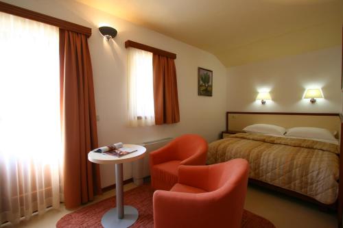 Villa Segetski Dvori في تروغير: غرفة نوم بسرير وكرسي وطاولة