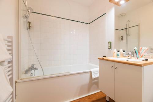 a white bathroom with a tub and a sink at Cerise Nantes Atlantis in Saint-Herblain