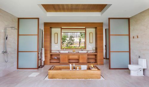 a bathroom with a tub and a toilet and a sink at FLC Luxury Resort Quy Nhon in Quy Nhon