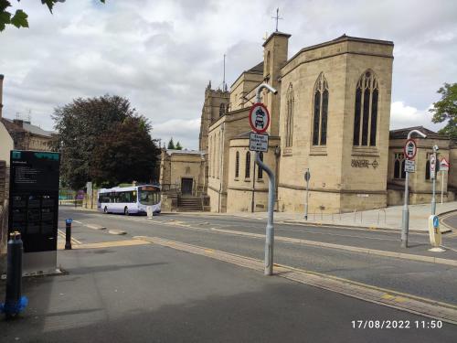 a bus driving down a street in front of a church at Sky Apartments in Bradford