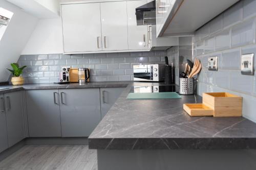 cocina con armarios blancos y encimera en Sky Apartments, en Bradford