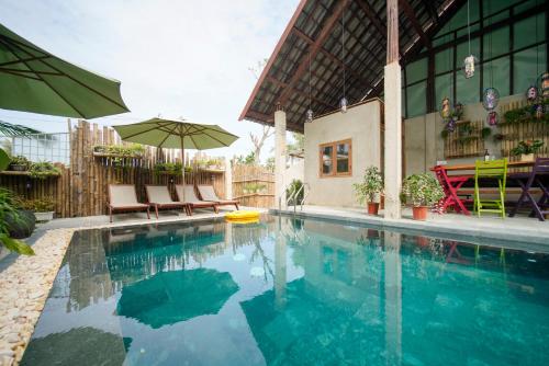 une piscine avec des chaises et un parasol dans l'établissement HA Devan Hoian Pool Villa, à Hội An