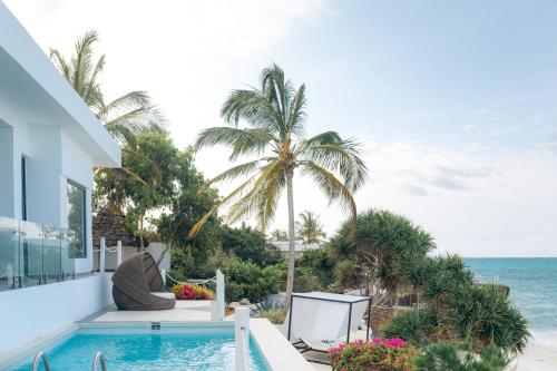 a house with a swimming pool next to the ocean at Safira Blu Luxury Resort & Villas in Nungwi