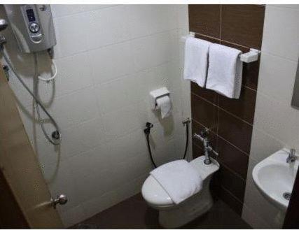 a bathroom with a toilet and a sink with towels at Dynasty Inn - Wakaf Che Yeh in Wakaf Che Yeh