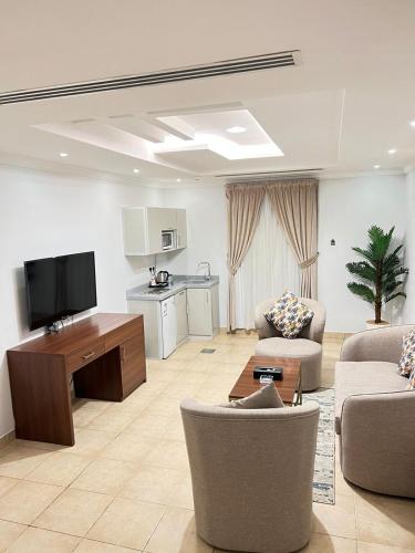 ein Wohnzimmer mit zwei Stühlen, einem Fernseher und einem Tisch in der Unterkunft شقق مخدومة المرسلات in Riad