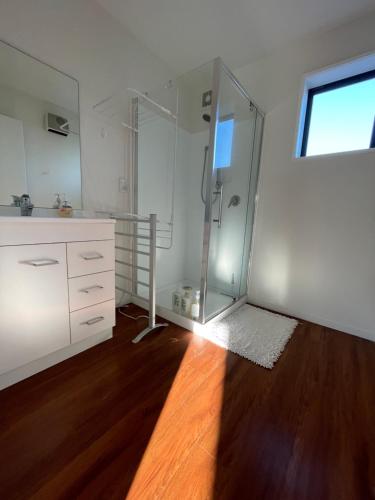 baño con ducha de cristal y suelo de madera. en Quiet & New - Planted & Characteristic - 7Vhouse, en Christchurch