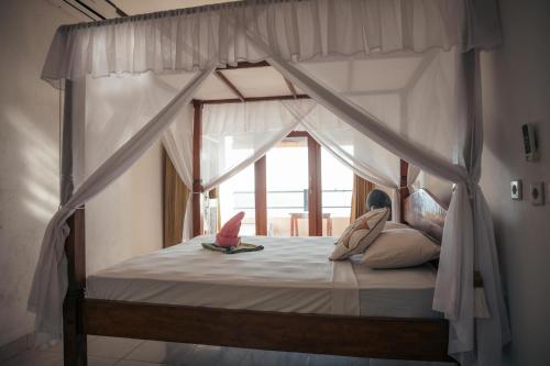 a bedroom with a canopy bed with a window at Bukit Indah Homestay in Amed
