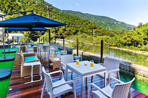 a patio with tables and chairs and an umbrella at Kurobe UnazukiOnsen Togen in Kurobe