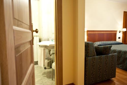 a bathroom with a bed and a sink and a door at Albergo Lo Scrigno in Pescocostanzo