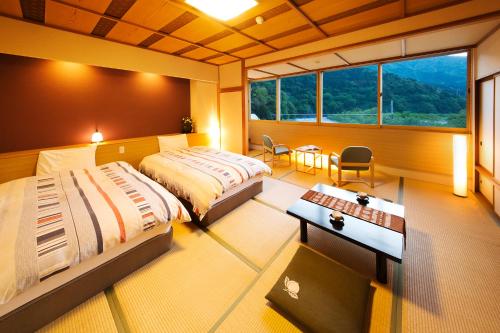 a bedroom with two beds and a desk and a window at Kurobe UnazukiOnsen Togen in Kurobe