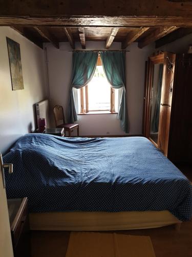 een slaapkamer met een blauw bed en een raam bij Grand gîte à la campagne in Missé