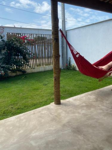 a red hammock hanging from a palm tree in a yard at Casa de praia Prado Ba Doces magnólias in Prado