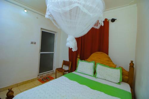 a bedroom with a bed with green and white pillows at Ambassador Bridge Motel in Jinja