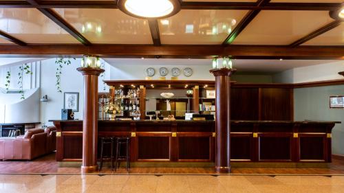 a bar in a room with columns and a couch at Hotel Violeta in Druskininkai