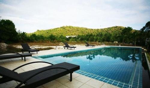 a large swimming pool with two lounge chairs at White@Sea Resort in Ban Phe