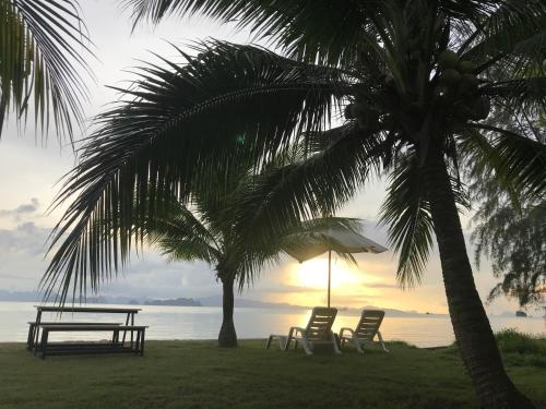 a picnic table and chairs under palm trees on the beach at Koh Yao Yai Sea Breeze House เกาะยาวใหญ่ซีบรีซเฮ้าส์ in Ko Yao Yai