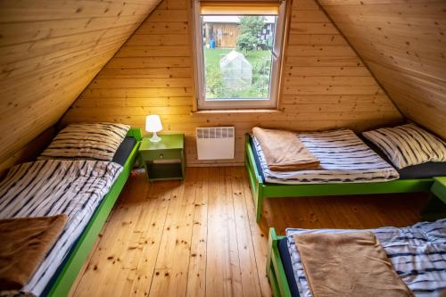 two beds in a wooden room with a window at Mały Kaletnik in Kaletnik