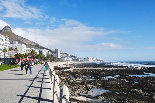 people walking along the beach near the ocean at Gorgeous George by Design Hotels ™ in Cape Town