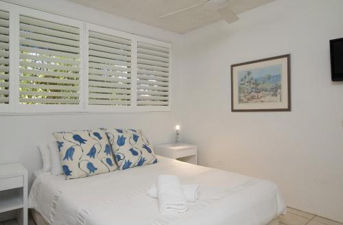 a white bedroom with a bed and a window at Sunseeker Holiday Apartments in Sunshine Beach
