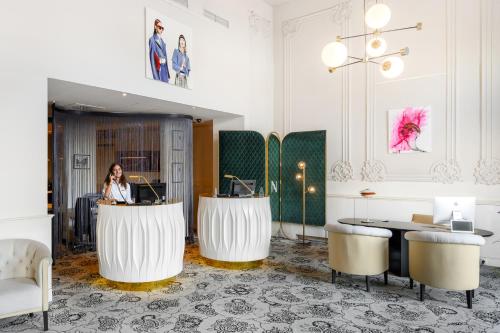 a woman sitting at a desk in a lobby at Hotel Nemzeti Budapest - MGallery in Budapest