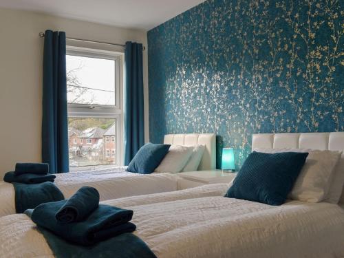 2 camas en una habitación con papel de pared azul en Bridge House, en Loftus