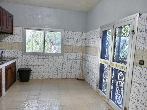 a bathroom with blue and white tiled walls and windows at RESIDENCE DU PELERIN - Villa l'écrin de verdure à Bandjoun in Bandjoun