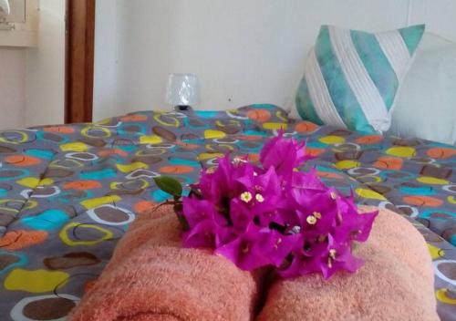 uma flor roxa sentada em cima de uma cama em appartement lagon blue em Mahébourg