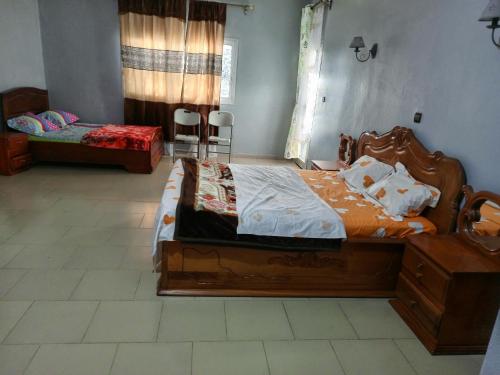 a bedroom with a large wooden bed in a room at RESIDENCE DU PELERIN - Villa l'écrin de verdure à Bandjoun in Bandjoun