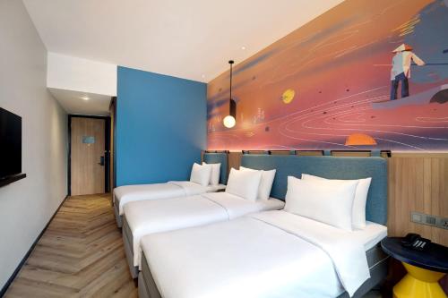 three beds in a room with a painting on the wall at ibis Styles Semarang Simpang Lima in Semarang
