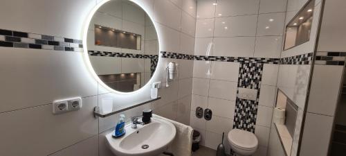 a bathroom with a sink and a mirror and a toilet at Adessa Apartment in Bad Mergentheim