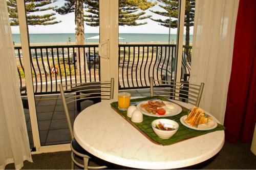 una mesa con bandeja de comida en un balcón con vistas a la playa en Beachfront Motel, en Napier