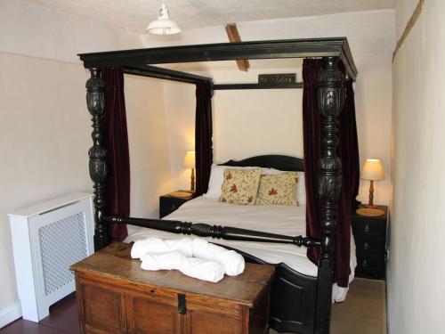 a bedroom with a canopy bed with towels on a table at Lavender Cottage in Methwold
