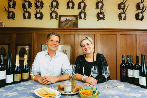 a man and a woman sitting at a table with wine bottles at wohnen auf dem Weingut - klein und fein in Maring-Noviand