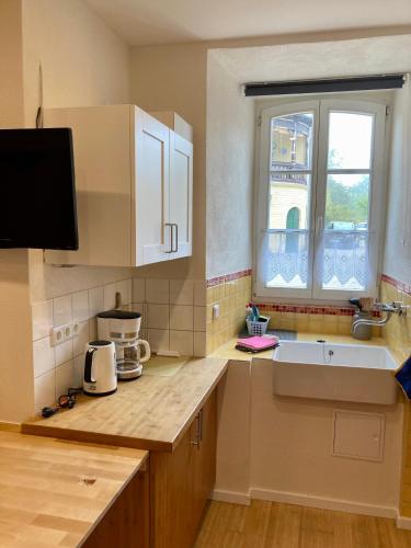 a kitchen with white cabinets and a sink and a window at wohnen auf dem Weingut - klein und fein - Wengertssube in Maring-Noviand