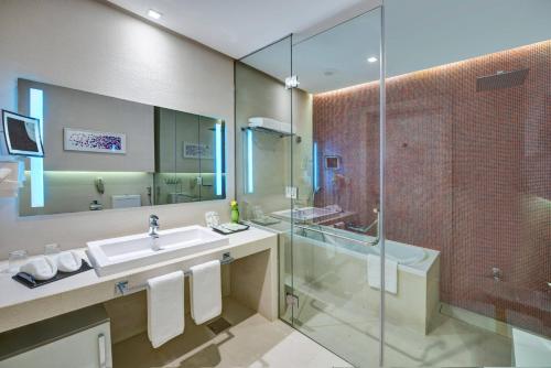 a bathroom with two sinks, a toilet and a bathtub at The Act Hotel Sharjah in Sharjah