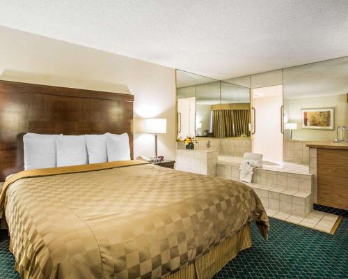 a hotel room with a bed and a bath tub at California Inn and Suites Bakersfield in Bakersfield