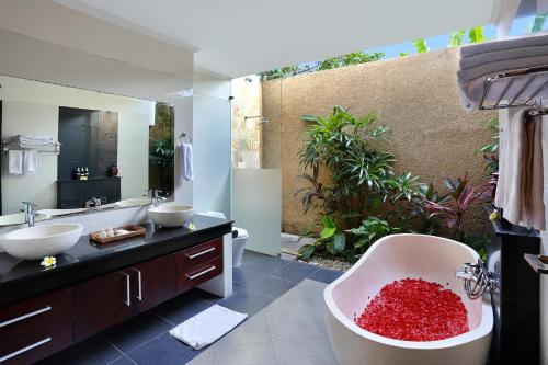 baño con 2 lavabos y bañera llena de rocas rojas en Askara Villa, en Canggu