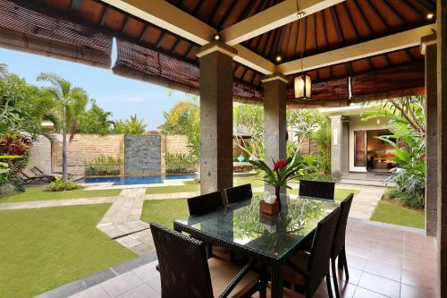 a dining room with a table and chairs on a patio at Askara Villa in Canggu