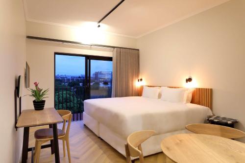 a bedroom with a large white bed and a table at Hyatt House Johannesburg Rosebank in Johannesburg