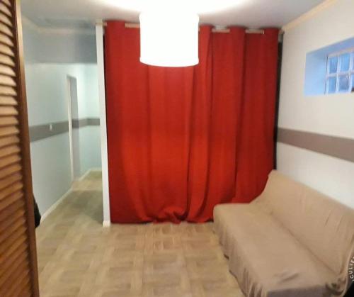 a living room with a red curtain and a couch at Farole,Gite de charme in Fort-Mahon-Plage
