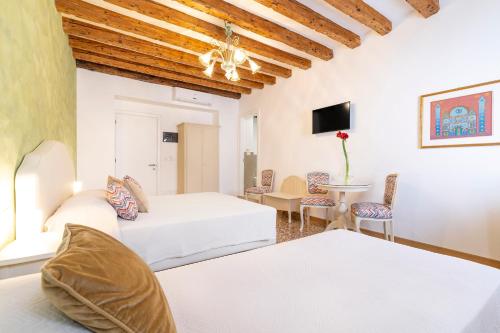 a hotel room with two beds and a table and chairs at Residenza San Silvestro in Venice