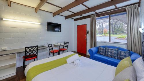 a bedroom with a bed and a couch and a table at Azalea Motel in Coonabarabran