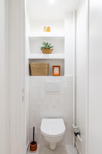 La salle de bains blanche est pourvue de toilettes et d'une plante. dans l'établissement Le Pitchou par Dodo à Cassis, à Cassis