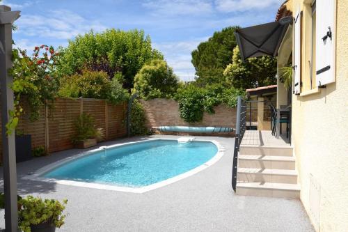 a swimming pool in a yard next to a building at Jolie Villa, Piscine, 10min centre ville, WIFI in Montpellier