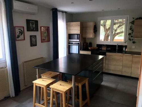 a kitchen with a black counter top and wooden stools at Jolie Villa, Piscine, 10min centre ville, WIFI in Montpellier