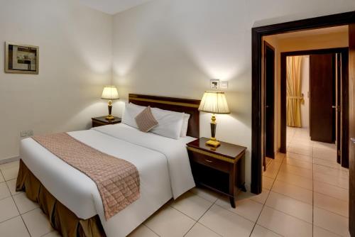 a bedroom with a large white bed and two lamps at Al Hayat Hotel Apartments in Sharjah