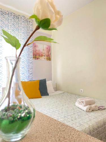 a vase with a flower on a table with a bed at Kozani elegant. Διαμέρισμα στο κέντρο της κοζάνης in Kozani