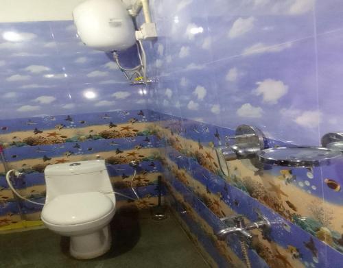 ein Bad mit einem WC und einer blauen Wand in der Unterkunft Kasturi Farmstay by StayApart in Bijanbāri Bāzār